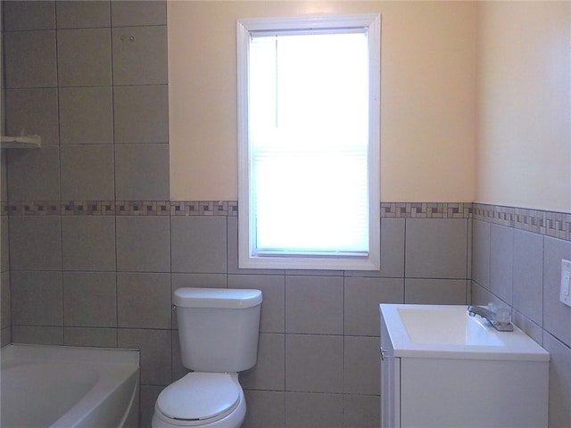 bathroom with a washtub, toilet, tile walls, and sink