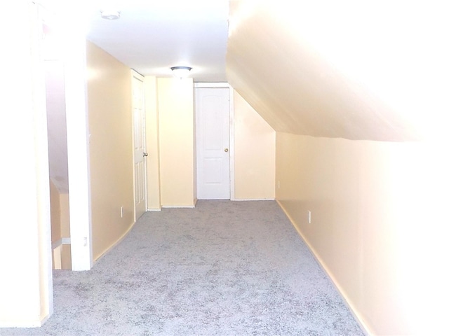 additional living space with light colored carpet and vaulted ceiling