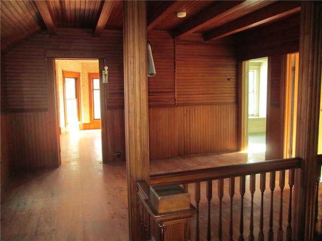 hallway featuring lofted ceiling with beams, wood walls, light hardwood / wood-style flooring, and wood ceiling