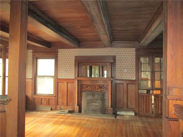 unfurnished living room with beam ceiling, hardwood / wood-style floors, wood ceiling, and a brick fireplace