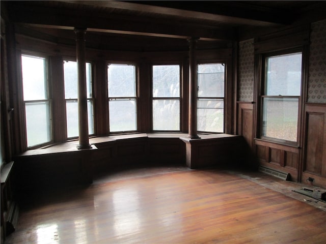 unfurnished sunroom with beam ceiling, decorative columns, and a wealth of natural light