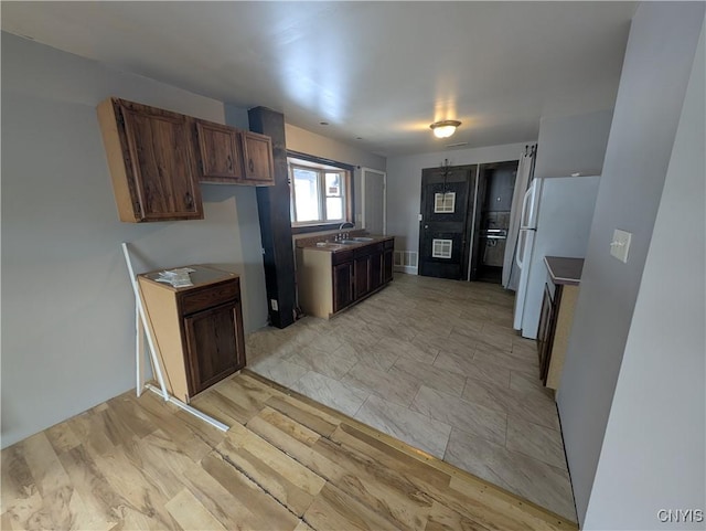 kitchen with white refrigerator, light hardwood / wood-style flooring, and sink