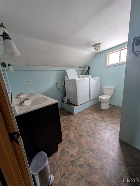 bathroom featuring washing machine and clothes dryer, vanity, lofted ceiling, and toilet