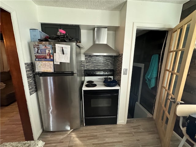 kitchen with stainless steel fridge, backsplash, wall chimney exhaust hood, white range with electric stovetop, and wood-type flooring