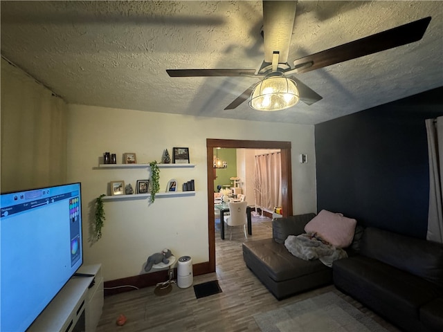 living room with ceiling fan, hardwood / wood-style floors, and a textured ceiling