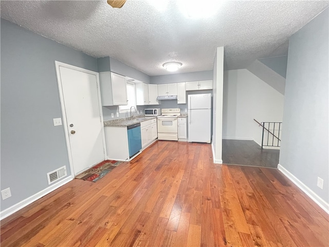 kitchen with white cabinetry, sink, a textured ceiling, white appliances, and light wood-type flooring