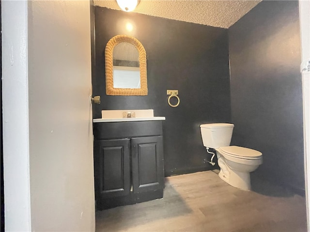 bathroom featuring vanity, a textured ceiling, hardwood / wood-style flooring, and toilet