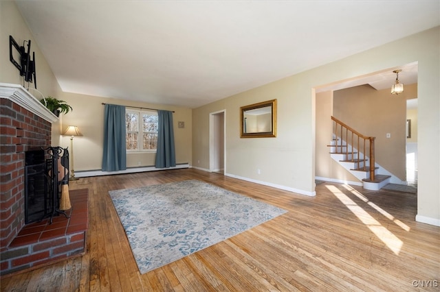 unfurnished living room with hardwood / wood-style floors, a brick fireplace, and a baseboard radiator