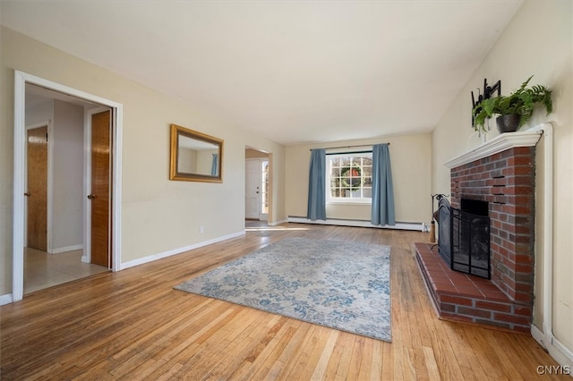 living room featuring a brick fireplace, light hardwood / wood-style flooring, and a baseboard heating unit