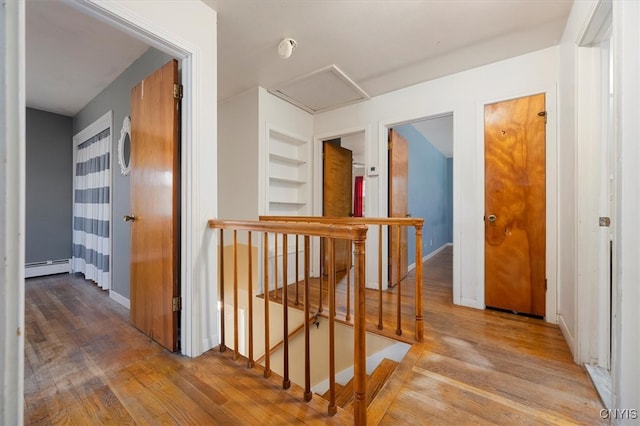 hall with built in shelves, light hardwood / wood-style floors, and a baseboard radiator