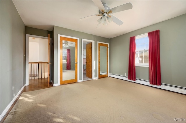 unfurnished bedroom with carpet flooring, ensuite bathroom, ceiling fan, and a baseboard heating unit