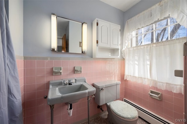 bathroom featuring toilet, baseboard heating, and tile walls