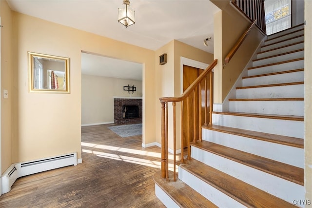 stairway featuring a fireplace, hardwood / wood-style floors, and a baseboard radiator