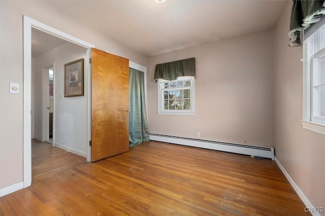 unfurnished bedroom with light hardwood / wood-style flooring and a baseboard heating unit