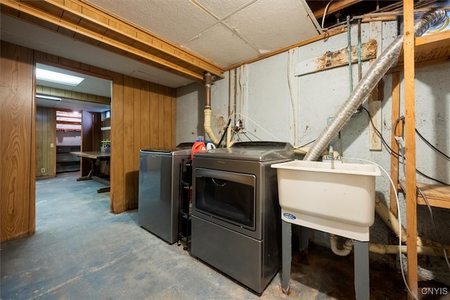 clothes washing area with independent washer and dryer, sink, and wooden walls