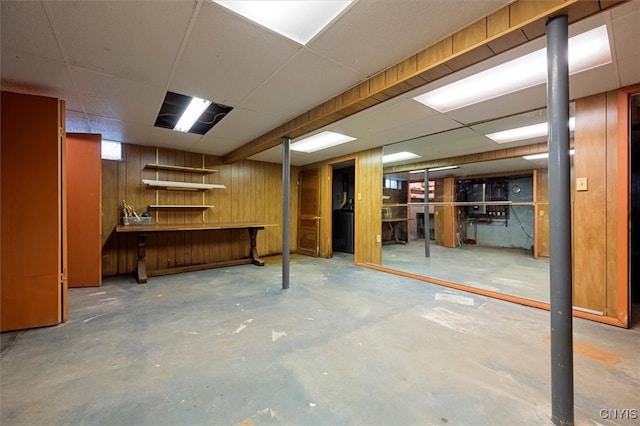 basement with a paneled ceiling and wood walls