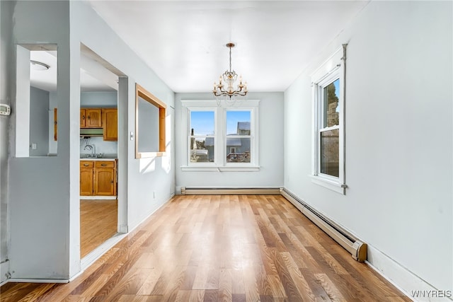 unfurnished dining area with sink, light hardwood / wood-style flooring, a notable chandelier, and a baseboard heating unit