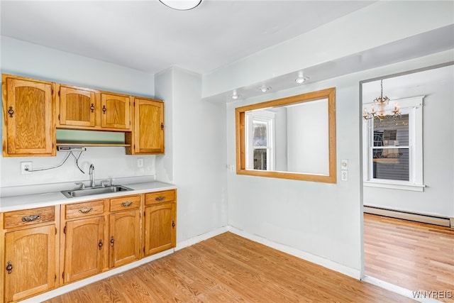 kitchen featuring baseboard heating, sink, light hardwood / wood-style floors, and a notable chandelier