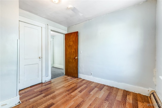 unfurnished bedroom with a baseboard radiator and light wood-type flooring