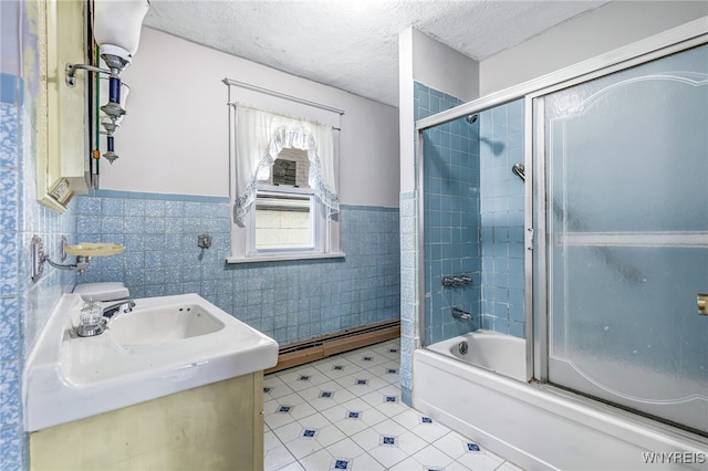 bathroom with vanity, combined bath / shower with glass door, tile walls, and a baseboard heating unit