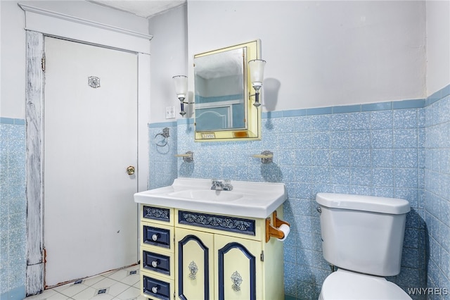 bathroom featuring toilet, vanity, tile patterned floors, and tile walls