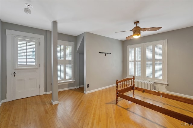 bedroom with ceiling fan, radiator, and light hardwood / wood-style flooring