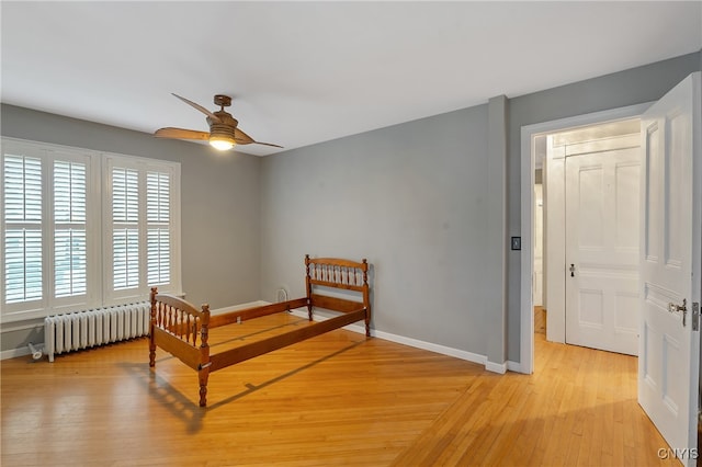 bedroom with light wood-type flooring, radiator, and ceiling fan