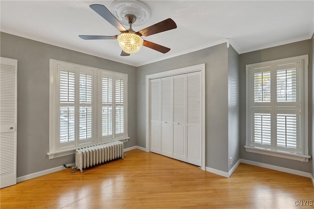 unfurnished bedroom with ceiling fan, radiator heating unit, light hardwood / wood-style floors, and ornamental molding