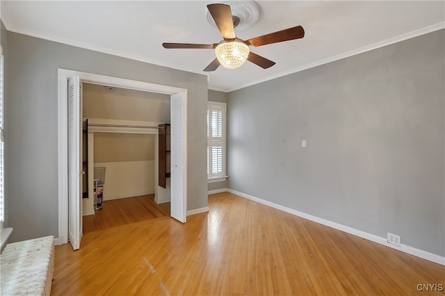 unfurnished bedroom featuring ceiling fan, wood-type flooring, ornamental molding, and a closet