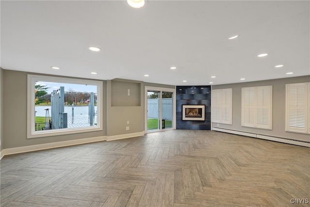 unfurnished living room with baseboard heating, a water view, and light parquet floors