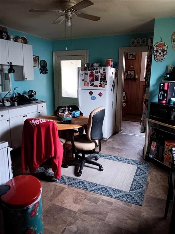 interior space with white cabinets, white refrigerator, ceiling fan, and sink