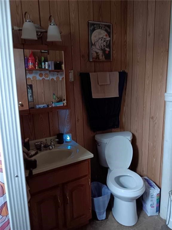 bathroom with wood walls, vanity, and toilet