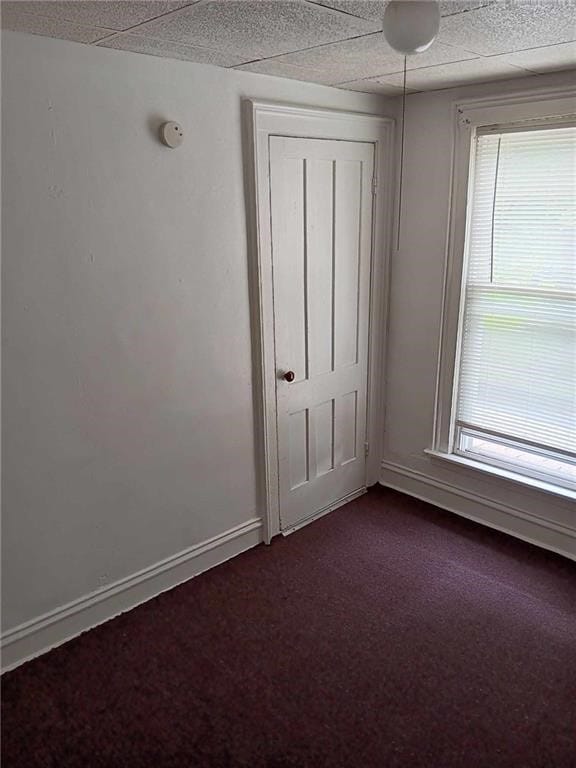 unfurnished bedroom with dark colored carpet and multiple windows