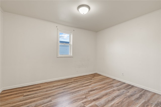 spare room with light wood-type flooring and crown molding