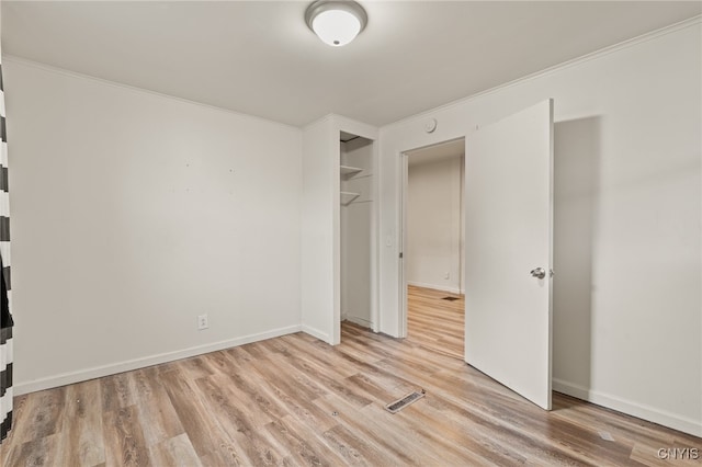 unfurnished bedroom with light hardwood / wood-style floors, ornamental molding, and a closet