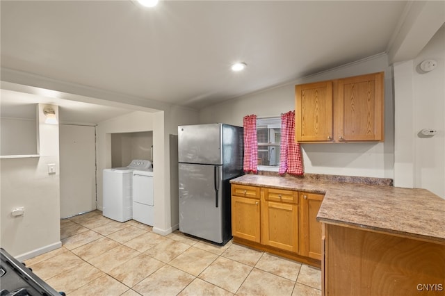 kitchen featuring washing machine and dryer, light tile patterned floors, ornamental molding, kitchen peninsula, and stainless steel refrigerator