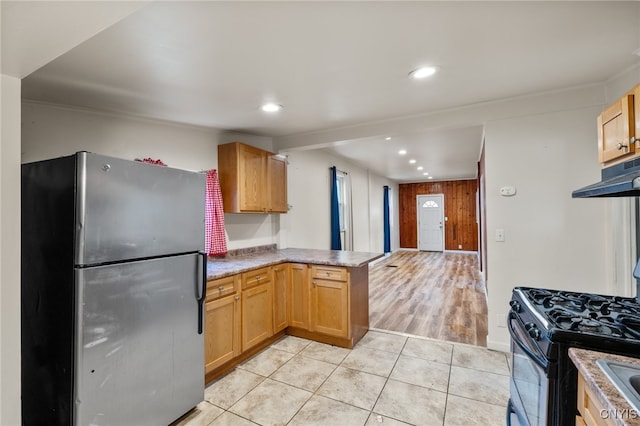 kitchen with ornamental molding, black gas range oven, light tile patterned flooring, kitchen peninsula, and stainless steel refrigerator