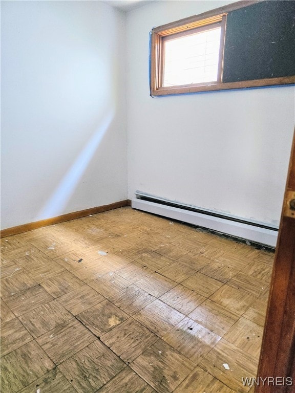 spare room with hardwood / wood-style flooring and a baseboard heating unit