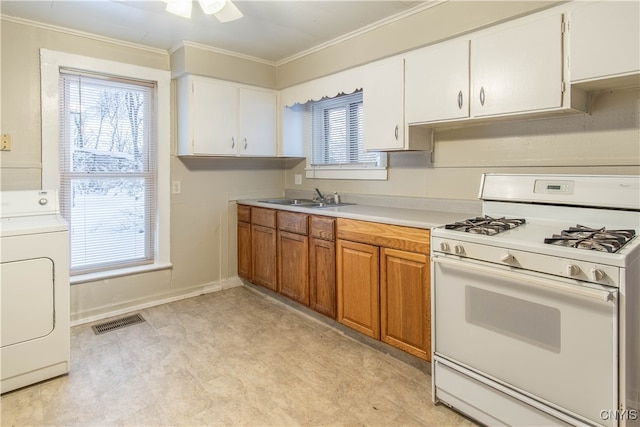 kitchen featuring white gas range, crown molding, sink, washer / dryer, and white cabinetry