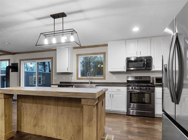 kitchen with pendant lighting, white cabinetry, and stainless steel appliances