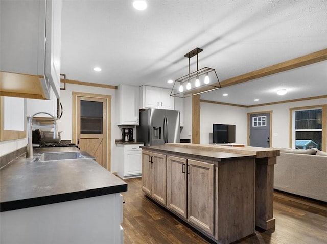 kitchen with sink, white cabinets, hanging light fixtures, and stainless steel fridge