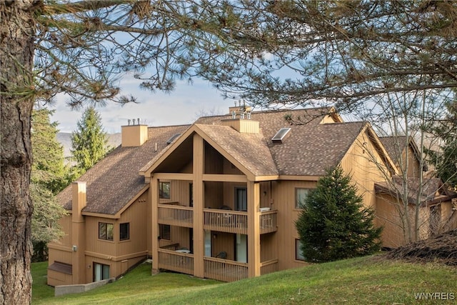 rear view of house with a balcony and a lawn