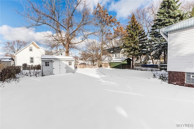 yard layered in snow featuring a storage shed