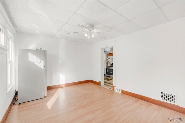 empty room with a paneled ceiling, ceiling fan, and light hardwood / wood-style flooring