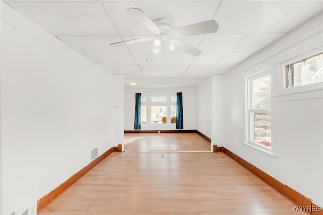 unfurnished room featuring light wood-type flooring, a drop ceiling, and ceiling fan