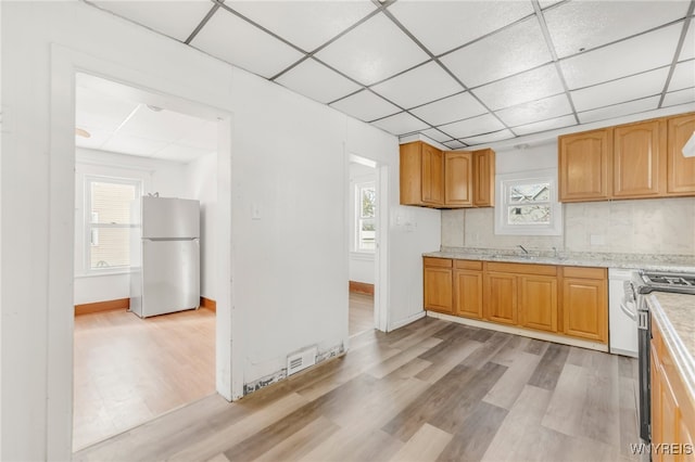 kitchen featuring light wood-type flooring, white refrigerator, plenty of natural light, and stainless steel range oven