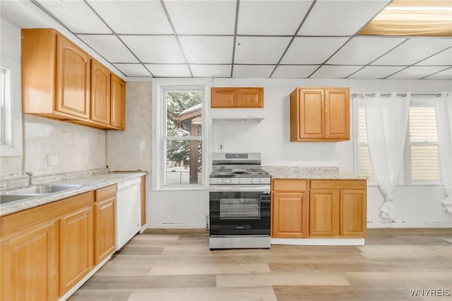 kitchen with a paneled ceiling, white dishwasher, stainless steel range with gas cooktop, sink, and light hardwood / wood-style flooring