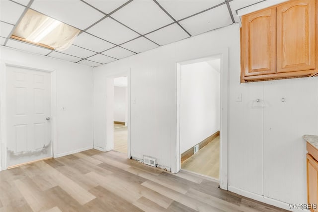 basement featuring a paneled ceiling and light hardwood / wood-style flooring