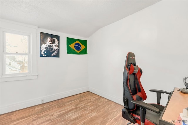 office featuring a textured ceiling, light hardwood / wood-style floors, and lofted ceiling