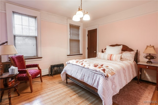 bedroom with a chandelier, radiator, and light hardwood / wood-style flooring